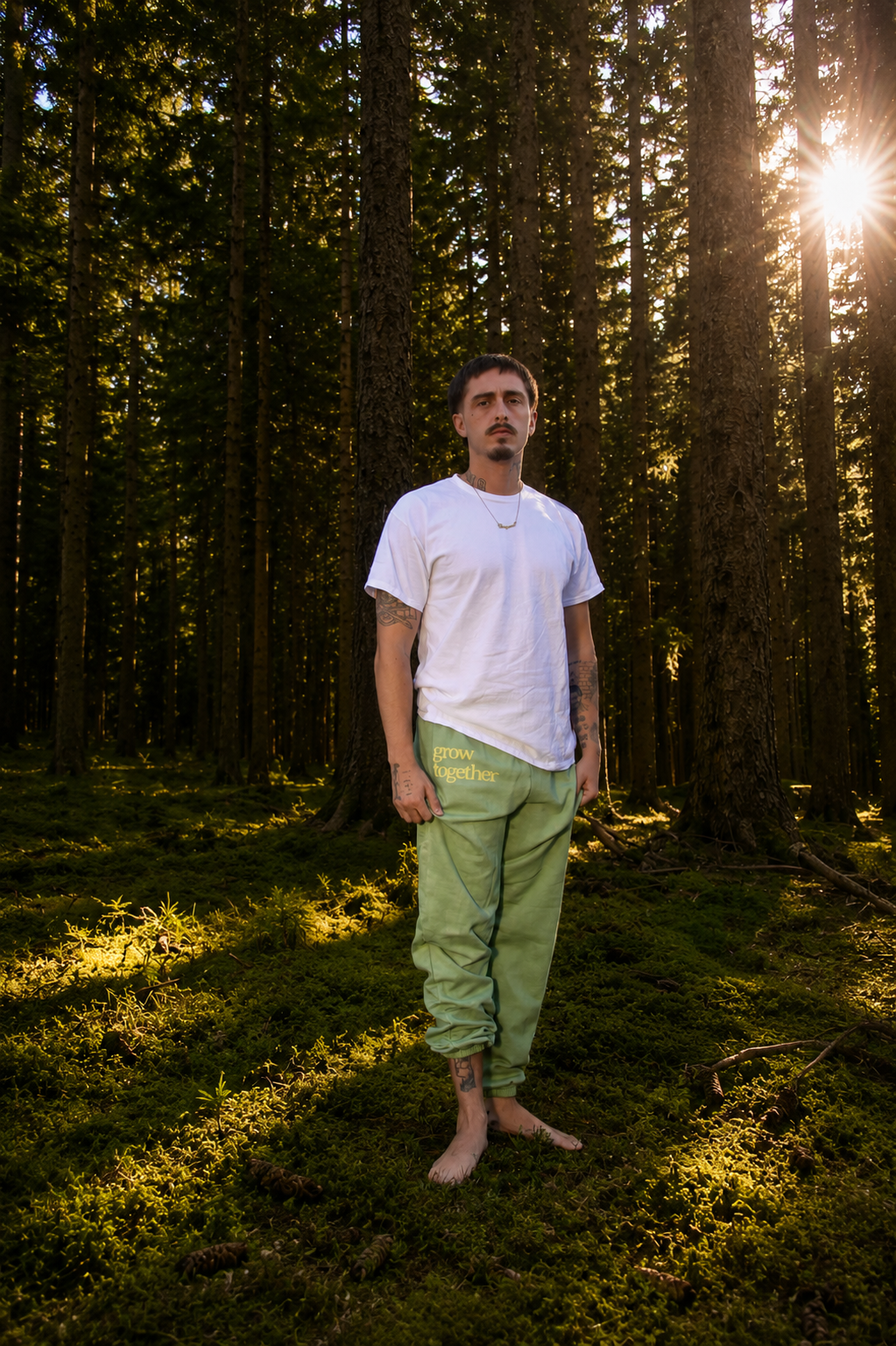 A man wearing green sweatpants in a sunlit forest